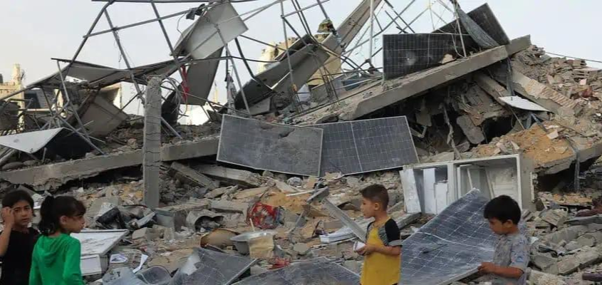 Children near destroyed solar panels in Gaza